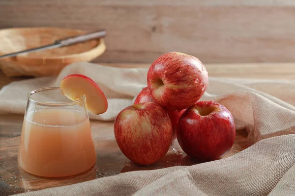 Apple Juice in the glass on wooden table with Gala Apple background. Fruits juice concept.