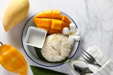 Beyaz masa arkaplanındaki beyaz tabakta hindistan cevizi sütü ile mango yapışkanı pilavı. Tayland 'da Ünlü Popüler Tatlı.