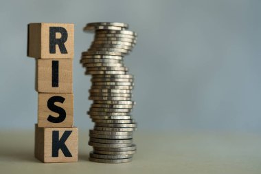 Bir yığın RISK küpü ve bozuk para yan yana. Risk yönetimi ve iş yatırımları değerlendirmesi, öngörülemeyen kayıpları kontrol etme ve mali güvenlik inşa etme amaçlı riskli plan analizinde strateji.