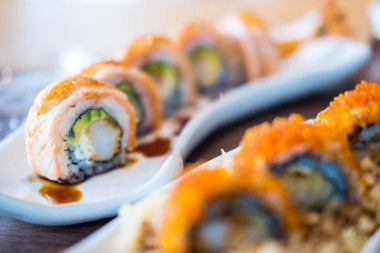 Lezzetli suşi rulosu ve bir tabakta servis edilen avokado. Japon yemeği..