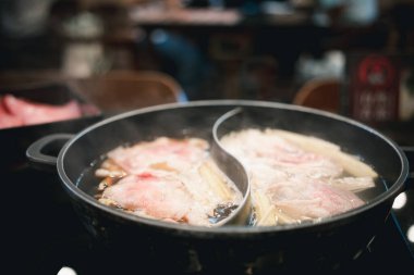 Japon restoranında shabu shabu sukiyaki soslu et kaynıyor.