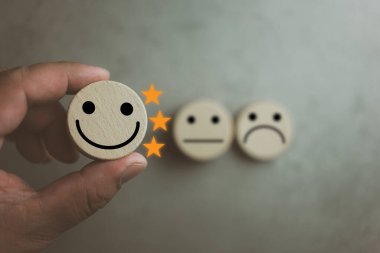 Müşteri memnuniyeti araştırması konsepti. Müşteri, mutlu yüz simgesi ve üç yıldızlı ahşap küpü seçiyor, memnuniyet için en iyi hizmet derecesi. Müşteri deneyimi kavramı