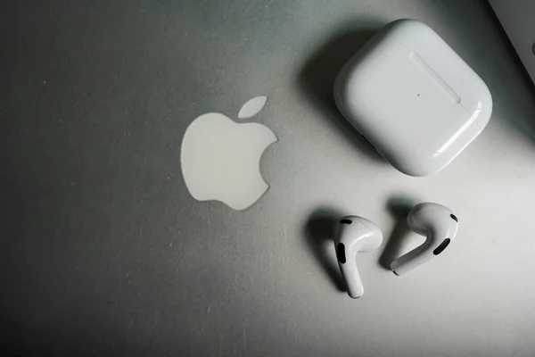 Bangkok, Tayland - 19 Kasım 2022: Apple AirPods 3 ve gri Macbook Pro şarj davası. Üst görünüm