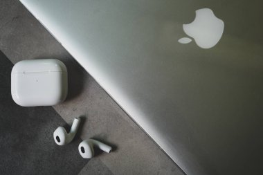 Bangkok, Tayland - 21 Kasım 2022: Apple AirPods 3 ve gümüş bir Macbook Pro 'nun yanına yerleştirilmiş şarj çantası. Üst görünüm