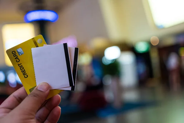 Man holding a credit card with two tickets to the cinema. Buy online with a debit or credit card. Cinema concept. Credit card to make payments cashless wallet of e-money.