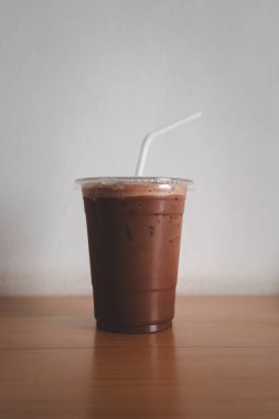 Kahve dükkanının ahşap masasında plastik bardakta buzlu kahve..