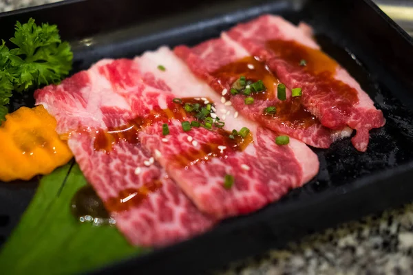 优质生日本牛肉片酱汁 撒上白芝麻籽和切碎的葱在黑盘上 — 图库照片