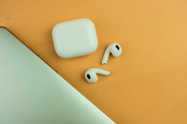 Bangkok, Tayland - 2 Aralık 2022: Turuncu arka planda Apple AirPods (3. nesil). Düz biçim veya üst görünüm.