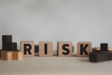 Risk değerlendirmesi, iş sonucunu kabul etme kararı belirsizlik, öngörülemez durum konsepti, RISK kelimesinin alfabeyle oluşturulduğu küp tahta blok.