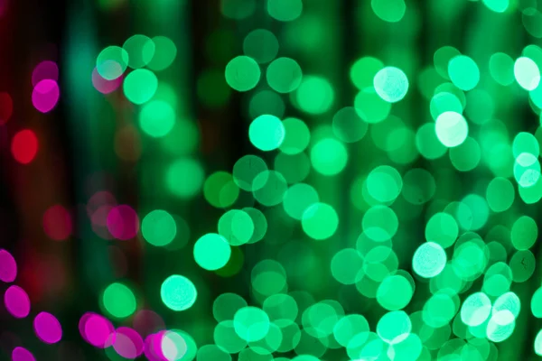 Defocused green and pink bokeh background lights at night.