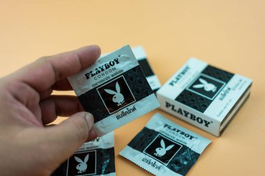 Samut Prakan, Tayland - 10 Aralık 2022: PLAYBOY Prezervatif numarası 52 mm olan erkek eli, (Playboy Black kravatlı) PLAYBOY marka prezervatif. Prezervatif, düzensiz yüzey.