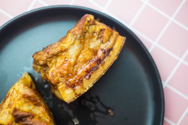 Kızarmış domuz göbeğinin siyah tabakta yakın görüntüsü..