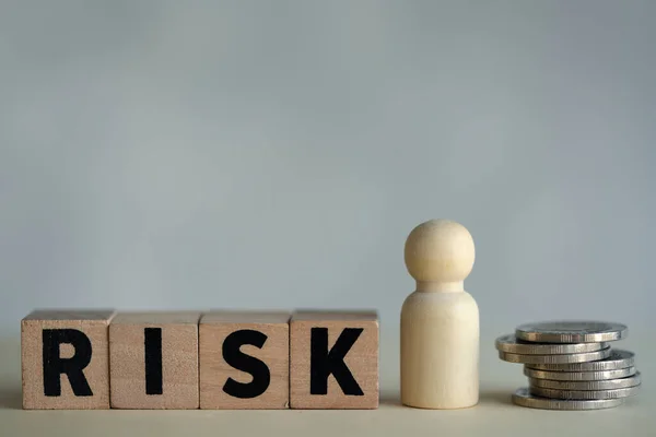 stock image Shape doll wooden peg dolls with RISK and coin. Risk assessment, decision to accept business result in uncertainty, unpredictable situation concept. Risk management concept.