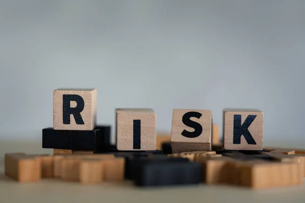 Risk assessment, decision to accept business result in uncertainty, unpredictable situation concept, cube wooden block with alphabet building the word RISK.
