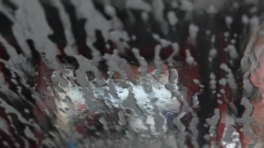 Araba temizlerken, otomatik oto yıkamada arabada otururken görüntüyü izle. Deterjan başvurusu. Arabadan ön cama bak.