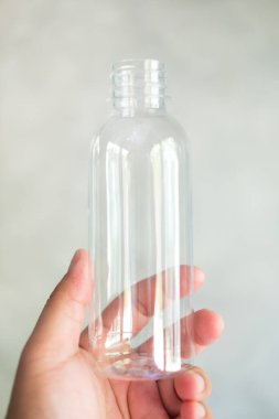 Elin boş plastik su şişesini tutuyor. Kapat.