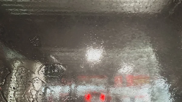 Foam, bubbles and water on the windshield of a car going through the carwash.