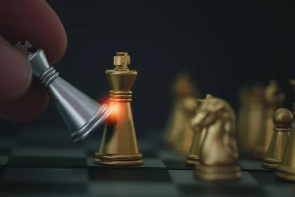 Close up shot hand of businessman moving silver chess to defeat a silver king chess and checkmate enemy. Business challenge competition winner and loser concept