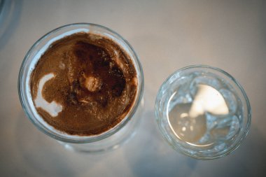 Kirli kahve buzlu sütlü buzlu sütlü kahve soğuk suyla servis edilen ahşap bar masasının ölçüsünde bir fincan kahveye atılmış espresso.