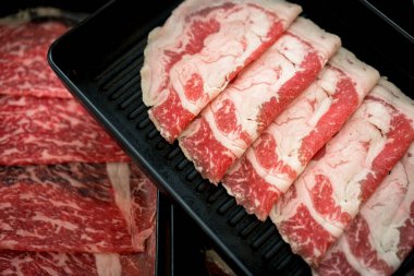 Buharlı gemi için hazırlanmış çiğ sığır eti. Siyah tepside servis edilen sıcak tencere sukiyaki.