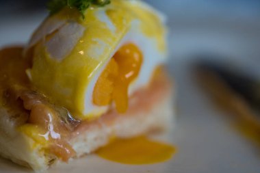 Close up smoked salmon egg Benedict. Selective focus. Eating eggs benedict in a white dish