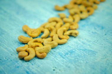 Close-up roasted cashew nuts on blue background.