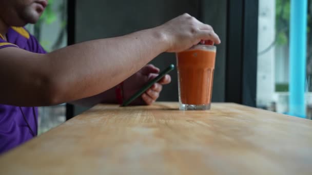 亚洲年轻人一边打电话一边在咖啡店喝茶 — 图库视频影像