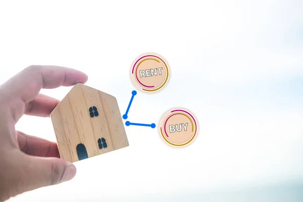 Man holding wood home and icon of Buy or Rent with copy space. real estate, decision between of buy or rent home
