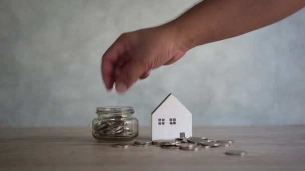 Geld Besparen Door Munten Een Pot Met Miniatuur Houten Huis — Stockvideo