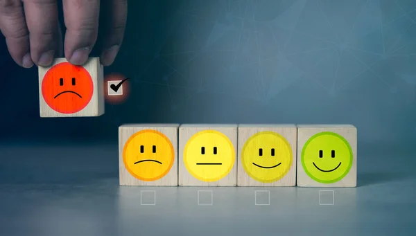 Customer service evaluation and satisfaction survey service rating concepts. Choose the wooden block with the unhappy face icon on wooden cube. Sad wooden dices with unhappy face emotion symbol