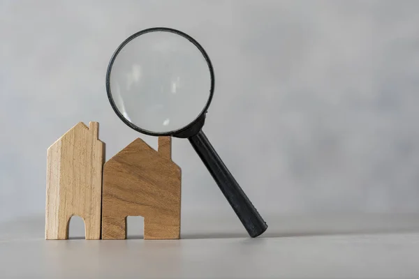 Two model houses and a magnifying glass. House selection, real estate concept. The best of house searching