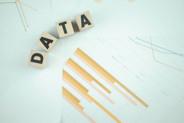 The word Data, alphabet on wooden cubes on paper graph background. Research study or information analysis, facts and knowledge for education or business.