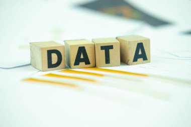 The word Data, alphabet on wooden cubes on paper graph background. Research study or information analysis, facts and knowledge for education or business.