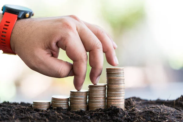 Fingers walking up on coins stack or money stack with coins growing from soil. The concept of financial and economic growth. Banking business growth, savings and productivity