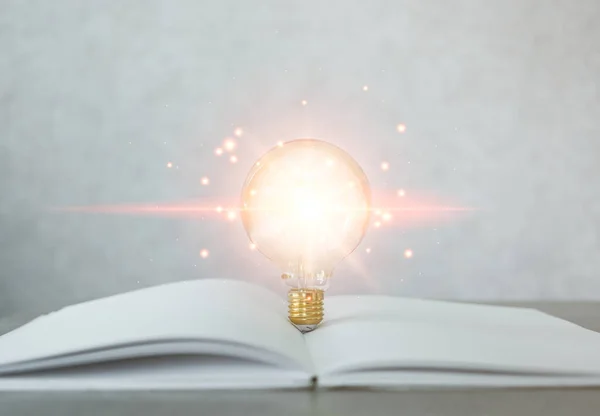 The light bulb glowing on an open book, the idea of inspiration from reading, innovation idea concept. Self-learning or education knowledge and business studying concept. Lifelong learning