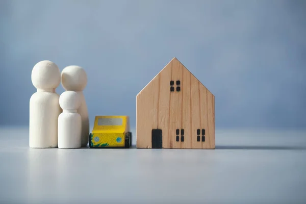 Wooden house with car and wooden peg dolls on grey marble table. Selective focus photo of the house. concept to build a family, marriage, and family planning. Success family