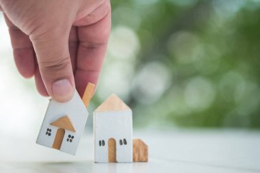 Mini ahşap ev modelini iki model arasından seçen bir adam mülk almayı planlıyor. En iyisini seç. Gayrimenkul yatırım işi. Araziyi almayı planlıyorum. En iyi ev. Mimarlık işi..