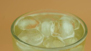 Temiz bardağa yakın çekim, bira ve soğuk buz küpü. Yavaş çekimde dönen bira bardağı..