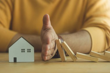 İş adamı el hareketi sigorta ve sigorta konsepti için yıkılan dominoyu korur. Hayat güvenliği finansal istikrar. Emlak sigortası. Domino zinciri meydan okuma ve koruma