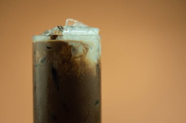 Close up a glass of iced Mocha coffee with ice cubes in transparent glass and milk texture. Cold summer drinks concept. Show the texture of milk and coffee