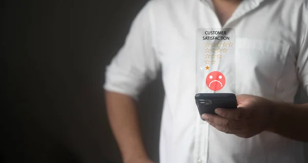 Concept of a bad experience or receiving bad service and customer dissatisfaction. Male rating dissatisfied give sad face icon and a one-star rating on his smartphone. Online satisfaction survey.