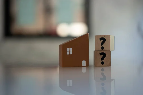 Question mark symbol on wood block and wooden brown house model. Real estate developer and managing property investment concept. Question for home concept