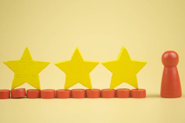 Tahta kırmızı figürler, tahta bebek, üç sarı tahta yıldızlı. Sıralama ve strateji konsepti. Müşteri tecrübesi, memnuniyet ve en iyi hizmet derecelendirme konsepti
