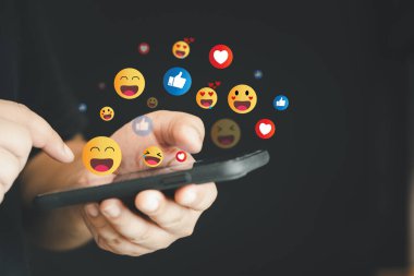 Akıllı telefon ekranının üstünde sosyal medya ikonları olan bir cep telefonu üzerinde sosyal medya kavramı kullanan bir kişi. Online toplum ve sosyal medya pazarlama stratejisi kavramı