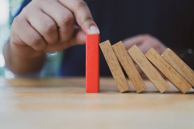 Adam eli sürekli devrilen kırmızı domino taşını durdurdu. İş çözümü kavramı. İş krizi etkisi veya risk koruma kavramı