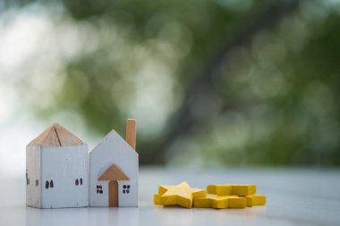 İki minyatür ahşap ev, arka planı bulanık olan sarı yıldızın yanına yerleştirilmiş. En iyi ev ve teklif evi. Gayrimenkul yönetimi konsepti