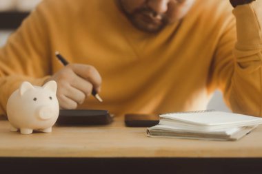 Asyalı adam, stres yüzünden kafasını kaldırıp muhasebe işleriyle uğraşıyor. Mali bilgiler ve borç problemleri hakkında endişeleniyor..