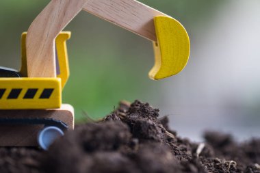 Toprakta sarı ahşap kazıcı var. Oyuncak inşaat malzemeleri. Kapat.