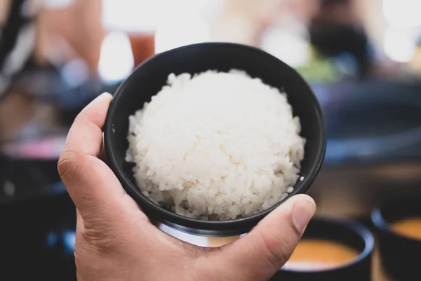 stock image Hand of man holding a white rice in the bowl. Close up