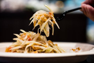 Somtum Thai yeşil papaya salatası baharatlı ve siyah çatalla tatlıdır.